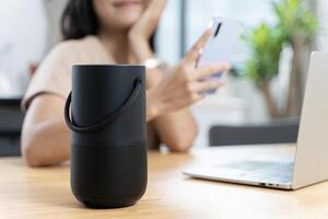 Close-up on hand using phone connecting portable speaker. Black Portable Wireless Bluetooth Speaker for Music. photo
