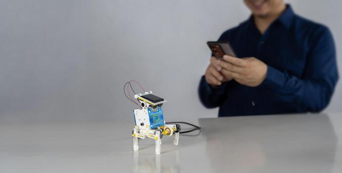 Young attractive students of mechatronics working on project. A plastic robot is in the hand of a student placed on the table. photo