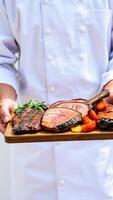 chef holds a board grilled meat photo