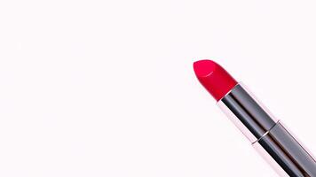 single bright red lipstick rests on a stark white background. photo