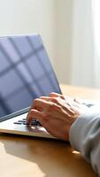 hand typing on a laptop with a window reflection photo