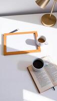 sunlight illuminates a white surface with a frame coffee pencils an open book. photo