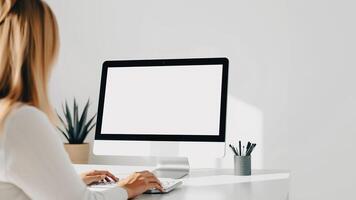 woman types on a keyboard at a desk with a blank computer screen photo