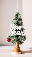 miniature christmas tree decorated with ornaments a new year sign photo
