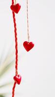three red hearts hanging from a braided cord photo