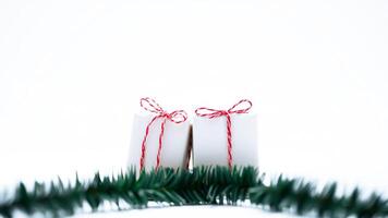 two white cylindrical objects tied with red white ribbon on a white surface with a green garland photo