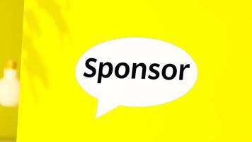 white speech bubble with the word sponsor on a yellow background photo