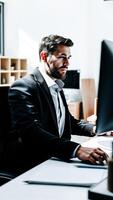 man a suit focuses on his work at a computer desk photo
