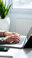 hands typing on a laptop a bright office setting photo