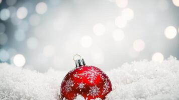 red christmas ornament with a snowflake design resting on white artificial snow photo