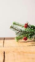 single pine branch with red berries resting on a wooden surface photo