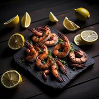 Grilled shrimp with herbs and lemon on a black slate photo