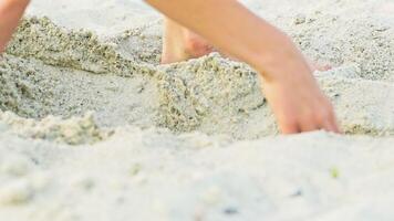 en unge får upp i en sandig grop med hans ben till mäta den och fortsätter till bygga ut dess längd och bredd. närbild. video