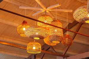 A collection of elegant and rustic hanging wicker lanterns, beautifully arranged to emit a warm, inviting glow. Perfect for enhancing cozy atmospheres in homes or stylish restaurants. photo