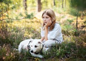 A child relaxing with a dog in a forest photo