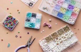Crafting with colorful beads on a flat workspace with tools and containers in bright daylight photo
