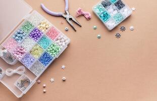 Crafting with colorful beads on a flat workspace with tools and containers in bright daylight photo