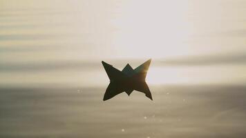 Paper boat floats alone with its reflection on the wavy water in the river at sunset. Beautiful rays of the evening sun falling on origami ship.Close-up video
