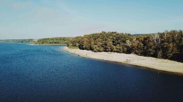 A beautiful resting place with a wide river and a sandy beach near green and long fields. Aerial view. Camera motion to back. video