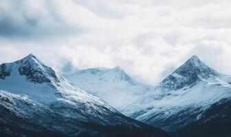 The mountains are covered in snow and the sky is cloudy photo