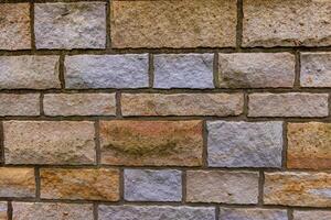 A close-up of a rough, textured stone wall with a variety of colors and sizes photo