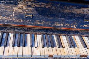 The image features piano keys with peeling paint against a black wooden background. The colorful keys are arranged in a staggered pattern, creating a unique and charming visual appeal. photo
