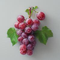a bunch of grapes with green leaves on a white surface photo