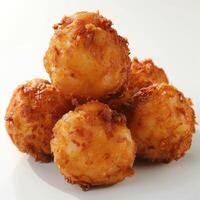 Three golden brown fried balls of food on a white surface. photo