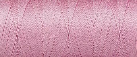 Texture of threads in a spool of pink color on a white background photo