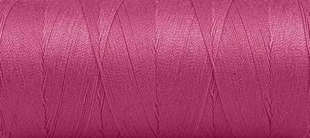 Texture of threads in a spool of pink color on a white background photo