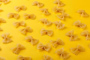 Different types and shapes of dry italian pasta on a yellow background photo