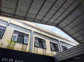 Banyumas, Indonesia - Oktober 25 2024, A view of a building Kantor Pelayanan Pajak Pratama Purwokerto with multiple windows, framed by a corrugated metal roof structure, under a clear blue sky. photo