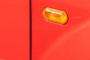 Driver side headlights on a car. close-up view of the front side flasher of a red car photo