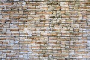 A wall made of stone blocks with a brownish color. The wall is very old and has a rough texture photo