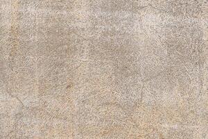 Close-up of a concrete or stone surface with rough texture, visible scratches, and wear marks. Predominantly light brown and gray tones. photo