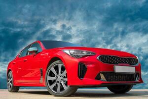Red car against the background of the evening sky. Stylish, modern, bright image of the car for design solutions. photo