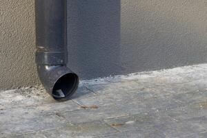 Rain runoff.New plastic drain pipe on a gray plastered wall photo
