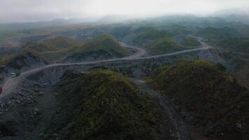 4k aerial footage of a barren area around a volcano with a winding road surrounded by piles of rocks and sand left over from the fall of volcanic material during an eruption. video