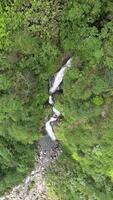 Drone flying from top to bottom, right above the Cikawah waterfall located in the Mount Halimun Salak National Park, Bogor, Indonesia. Flying in a vertical format shows the beauty of this waterfall. video
