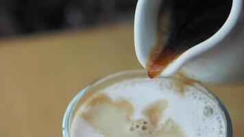 Expertly pouring rich coffee into a creamy latte topped with beautiful foam art design video