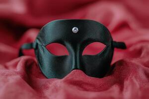 Elegant black masquerade mask with diamond on red fabric background photo
