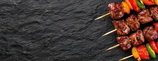 Grilled meat and vegetable skewers on dark slate background photo