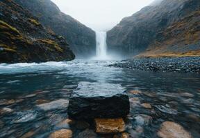 A waterfall in iceland with a rock in the water photo