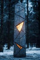 Illuminated stone sculpture in snowy forest photo