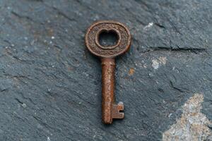 An old rusty key on a stone surface photo