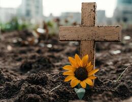 A cross in the ground with a sunflower photo