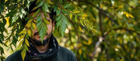 man partially hidden behind green leaves photo