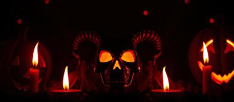 skull with horns glowing eyes surrounded by candles pumpkins photo