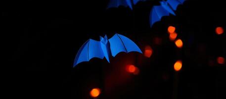 blue paper bat hangs against a blurred background lights photo