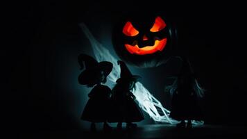 three witches stand before a glowing pumpkin photo